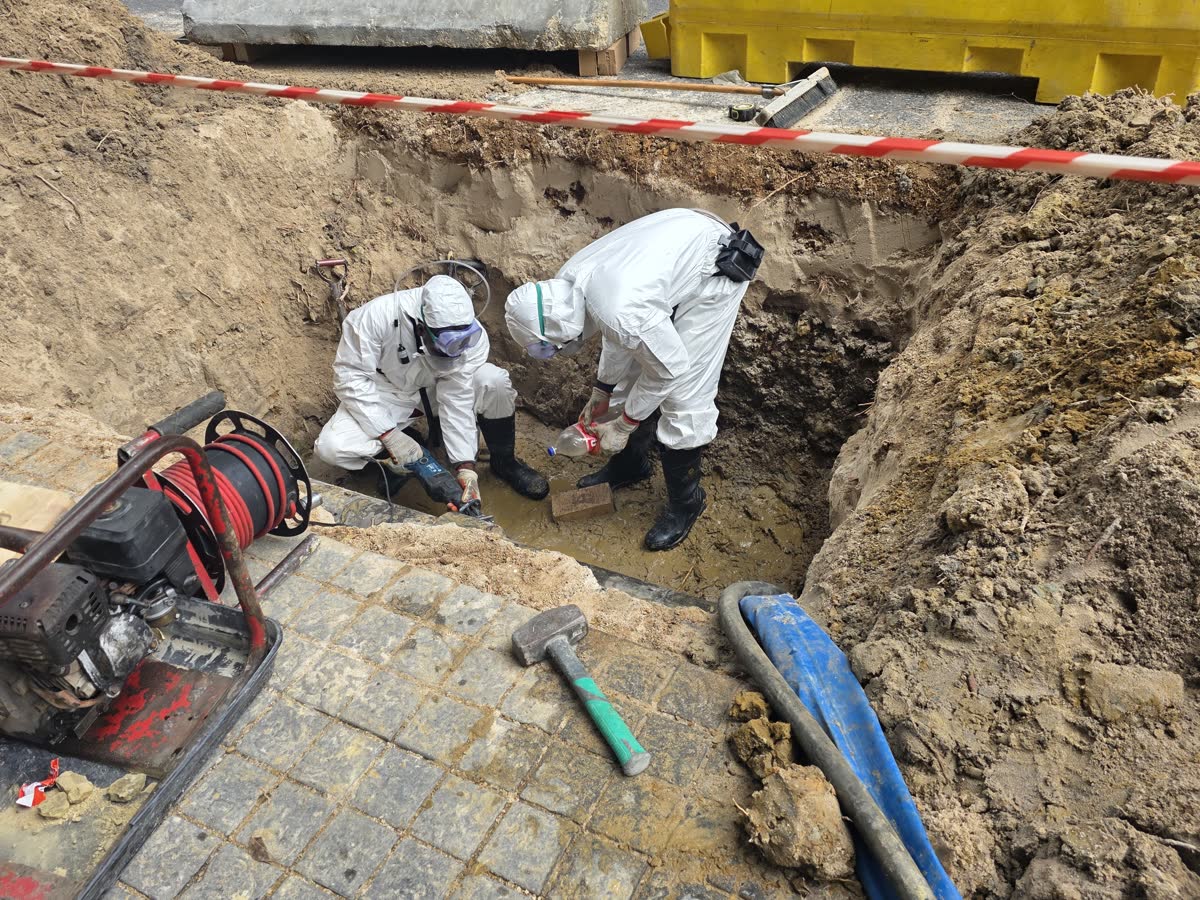 Two FN Building Projects workers in protective suits, gloves and respirators working in an excavation
